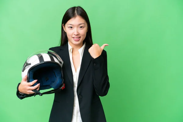 若いですアジアの女性とともにオートバイヘルメット上の隔離されたクロマキー背景を指す側に製品を提示します — ストック写真