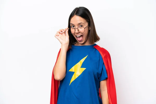 Super Hero caucasian woman isolated on white background with glasses and surprised
