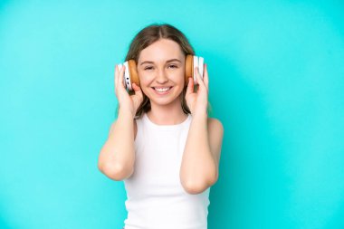 Blonde English young girl isolated on blue background listening music