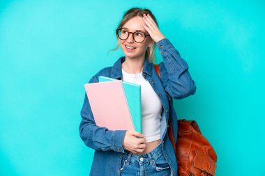 Genç bayan öğrenci, mavi arka planda izole edilmiş, çok gülümsüyor.