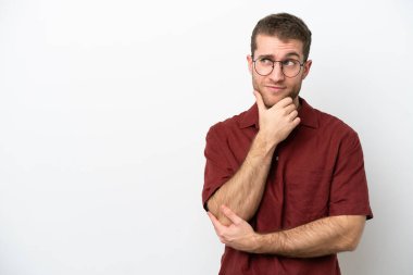 Beyaz arka planda izole edilmiş genç beyaz adam yukarı bakarken bir fikir düşünüyor.