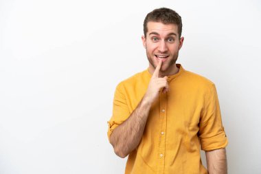 Beyaz arka planda izole edilmiş genç beyaz bir adam sessizlik işareti gösteriyor. Parmağını ağzına sokuyor.