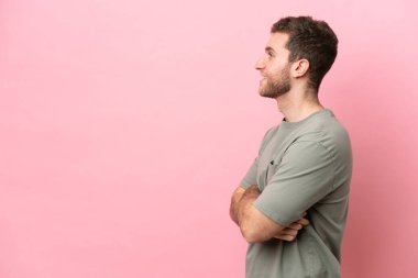 Young caucasian man isolated on pink background in lateral position