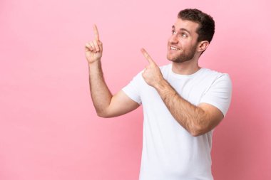 Pembe arka planda izole edilmiş genç beyaz adam işaret parmağıyla işaret etmek harika bir fikir.