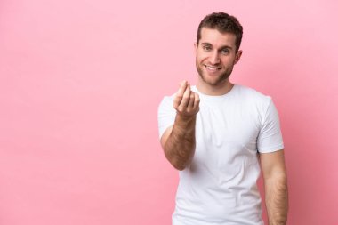 Pembe arka planda izole genç beyaz adam para hareketi yapıyor.