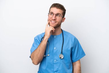 Young surgeon doctor caucasian man isolated on white background thinking an idea while looking up