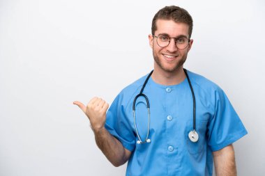 Young surgeon doctor caucasian man isolated on white background pointing to the side to present a product