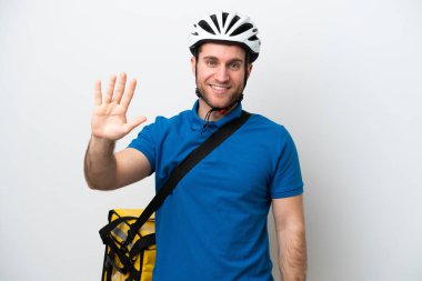 Beyaz arka planda termal sırt çantalı beyaz tenli genç adam parmaklarıyla beşi sayıyor.