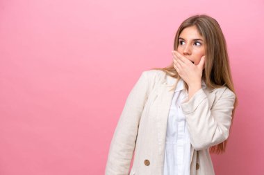 Young caucasian woman isolated on pink bakcground doing surprise gesture while looking to the side