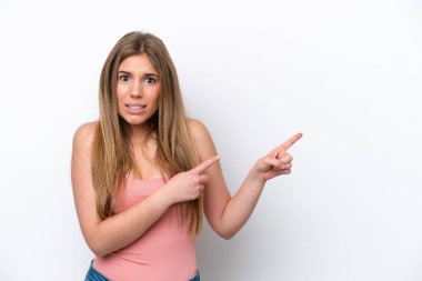 Young caucasian woman isolated on white bakcground frightened and pointing to the side
