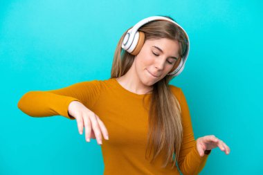 Genç beyaz kadın mavi arka planda izole edilmiş müzik ve dans dinliyor.