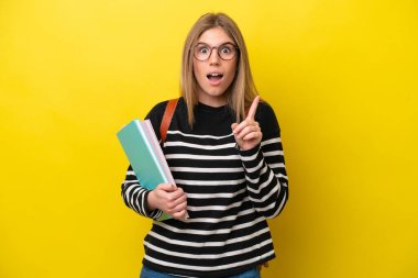 Young student woman isolated on yellow background background intending to realizes the solution while lifting a finger up
