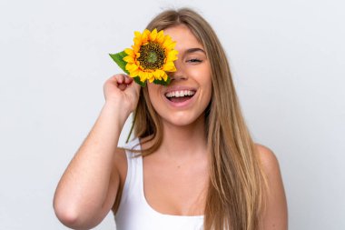 Beyaz arka planda izole edilmiş beyaz tenli genç bir kadın gülümserken elinde bir ayçiçeği tutuyor. Portreyi kapat