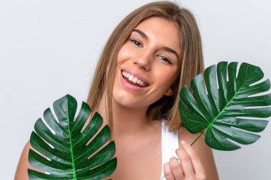 Beyaz arka planda izole edilmiş beyaz bir kadın elinde mutlu bir ifadeyle bir palmiye yaprağı tutuyor. Portreyi kapat