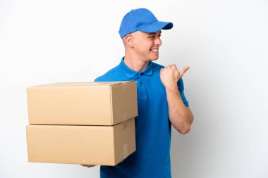 Young delivery Brazilian man isolated ops white background pointing to the side to present a product