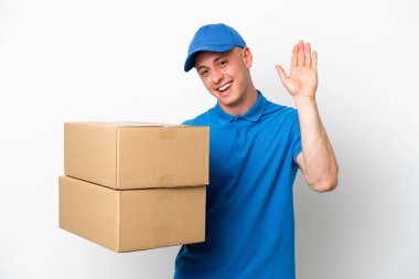 Young delivery Brazilian man isolated ops white background saluting with hand with happy expression