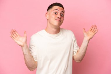 Pembe arka planda izole edilmiş genç Brezilyalı adam şüpheli hareketler yapıyor.