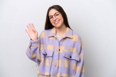 Young girl isolated on white background saluting with hand with happy expression