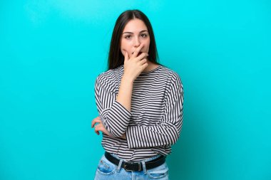 Mavi arka planda izole edilmiş genç beyaz kadın sağa bakarken şaşırdı ve şok oldu.