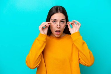 Young girl isolated on blue background With glasses and surprised expression