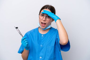 Beyaz arka planda izole edilmiş aletler tutan beyaz dişçi kadın yan tarafa bakarken sürpriz jest yapıyor.