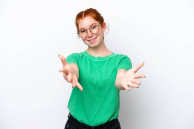Young reddish woman isolated on white background presenting and inviting to come with hand