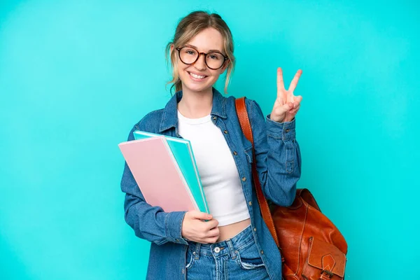 Νεαρή Μαθήτρια Απομονωμένη Μπλε Φόντο Χαμογελώντας Και Δείχνοντας Σύμβολο Της — Φωτογραφία Αρχείου