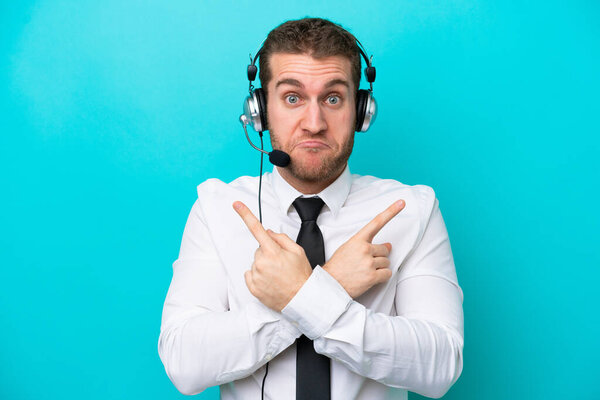 Telemarketer caucasian man working with a headset isolated on blue background pointing to the laterals having doubts
