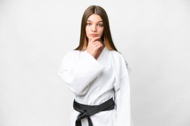 Teenager girl doing karate over isolated white background thinking