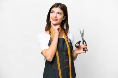 Seamstress woman over isolated white background thinking an idea while looking up
