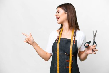 Seamstress woman over isolated white background pointing finger to the side and presenting a product
