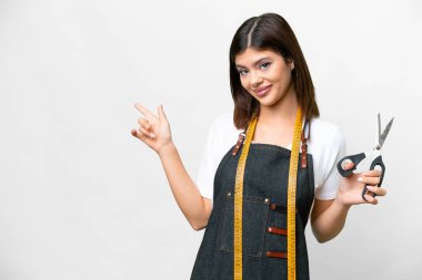 Seamstress woman over isolated white background pointing finger to the side
