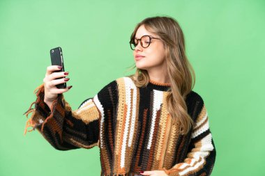 İzole edilmiş krom anahtar geçmişi olan genç bir kız selfie çekiyor.
