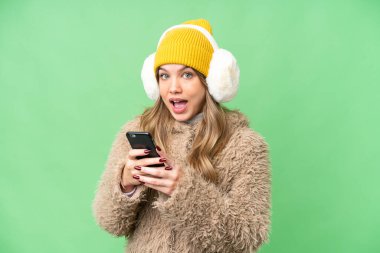 İzole edilmiş krom anahtar üzerine kış maskesi takan genç kız şaşırdı ve bir mesaj gönderiyor.