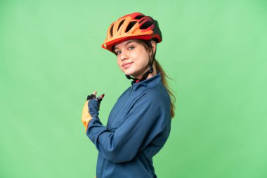 Genç bisikletçi kız izole edilmiş krom anahtar arka plan geriye işaret ediyor