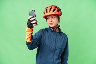 İzole edilmiş krom anahtar geçmişi olan genç bisikletçi kız selfie çekiyor.