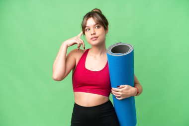 Genç sporcu kız yoga derslerine giderken izole edilmiş krom anahtar altyapısı üzerinde minder tutuyor. Şüpheleri ve düşünceleri var.