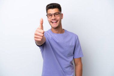 Beyaz arka planda izole edilmiş beyaz bir genç. Başparmakları havada. Çünkü iyi bir şey oldu.