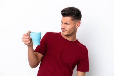 Beyaz arka planda, üzgün bir ifadeyle izole edilmiş bir fincan kahve tutan beyaz bir adam.