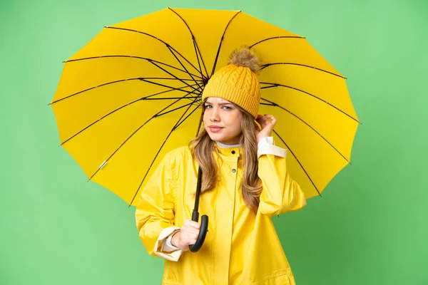 若いです女の子とともにレインプルーフコートと傘上の隔離されたクロマキー背景持っています疑問 — ストック写真