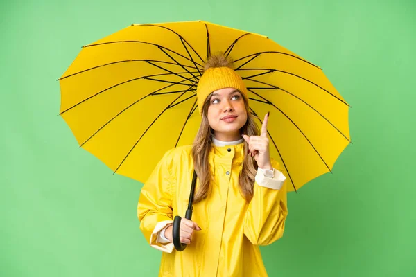 年轻姑娘穿着防雨外套 披着雨伞 遮挡着孤零零的色彩斑斓的背景 这说明了一个好主意 — 图库照片