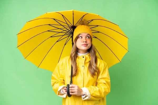 穿着雨衣 披着雨伞的小女孩 背景是孤零零的 仰望着天空 — 图库照片