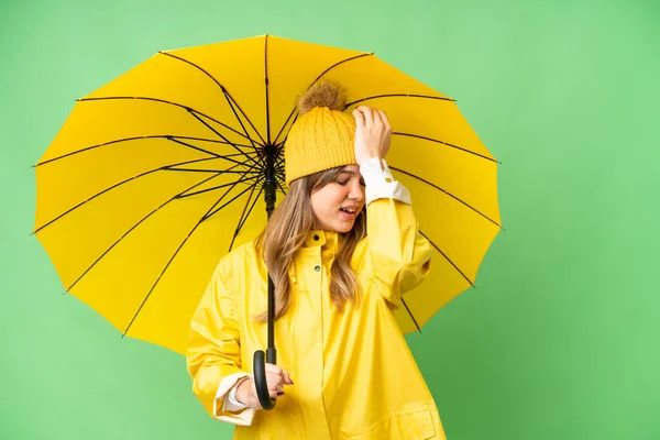 年轻姑娘穿着雨衣 披着雨伞 隐秘的色彩衬托着关键的背景 她已经意识到了什么 并打算解决这个问题 — 图库照片