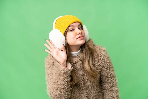 年轻姑娘披着冬衣 戴在孤立的彩色关键背景上 用手捂住耳朵听着什么 — 图库照片