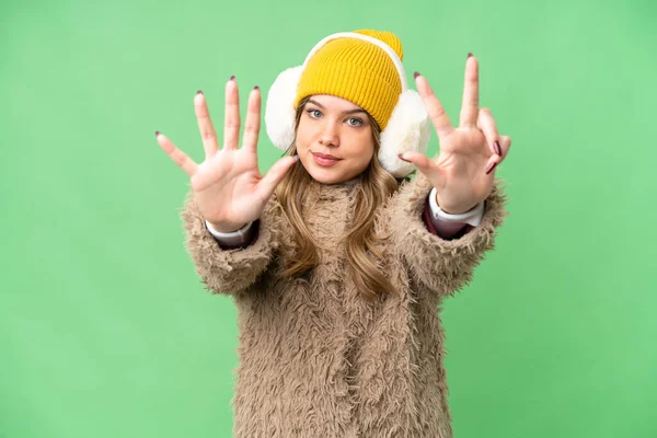 年轻姑娘穿着冬衣 戴在孤立的彩色关键背景上 用手指数着8 — 图库照片