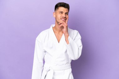 Mor arka planda karate yapan genç beyaz bir adam yukarı bakarken bir fikir düşünüyor.