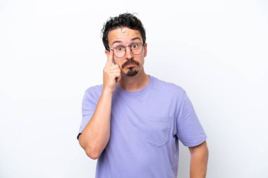 Bıyıklı genç adam beyaz arka planda izole edilmiş bir fikir düşünüyor.