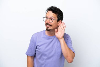 Bıyıklı genç adam beyaz arka planda izole edilmiş. Kulağına elini sürerek bir şeyler dinliyor.