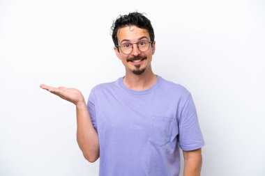 Bıyıklı genç adam beyaz arka planda izole edilmiş. Avucunda hayali bir şey tutuyor. Bir ilan vermek için.