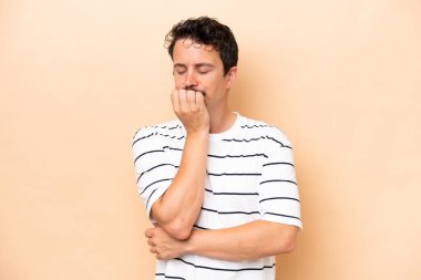 Beyazlı genç bir adam bej arka planda izole edilmiş. Şüpheleri var.